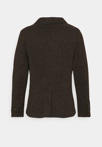 Brązowa, teksturowana dzianinowa kurtka z kołnierzem, długimi rękawami i mankietami na guziki. Posiada rozcięcie z tyłu dla większej swobody ruchów.