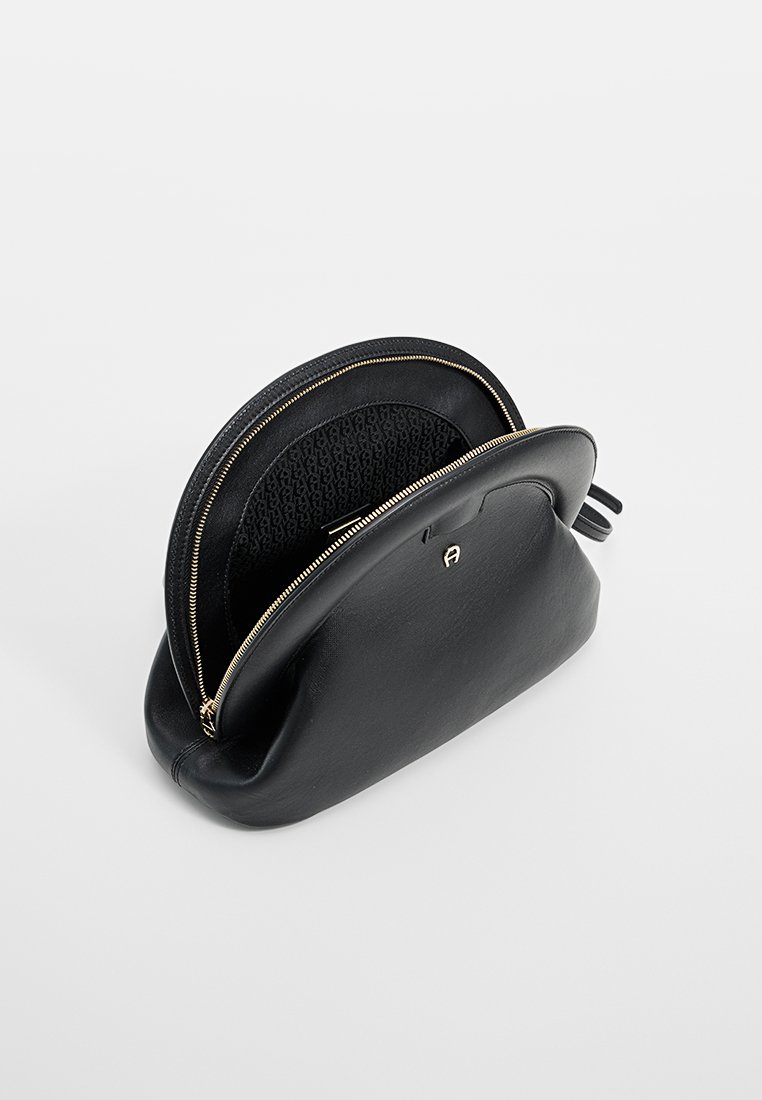 Schwarze Leder-Pouch mit runder Form, goldfarbenem Reißverschluss und einem strukturierten Innenfutter mit einem subtilen Muster.