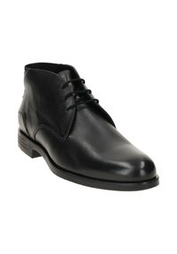Bottine noire en cuir avec trois œillets, bout arrondi et petit talon sur fond blanc.