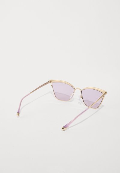 Lunettes de soleil en forme d'œil de chat avec une monture en métal doré, des verres violets clairs et des branches transparentes violettes. Présente de petites touches dorées sur les branches.