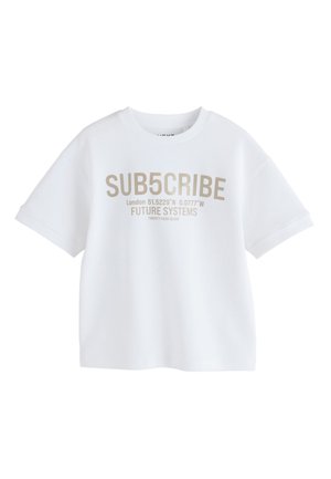 T-shirt blanc à manches courtes avec texte beige « SUB5CRIBE », coordonnées de Londres, « FUTURE SYSTEMS » et texte plus petit sur le devant.