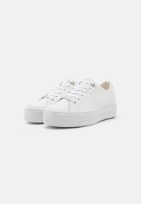 Baskets en cuir blanc avec une surface texturée, bout rond, semelle épaisse et fermeture à lacets. Accents argentés sur les lacets et les œillets.