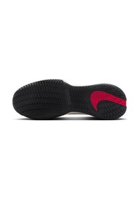 Musta kumipohja urheilusandaleista, jossa on sahalaitakuviokuviointi ja punainen Nike-raita lähellä kantapäätä.