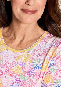 Multicolore bloempatron top met een zachte textuur, een ronde halslijn en een gele rand. Kleuren omvatten roze, geel, blauw en groen.