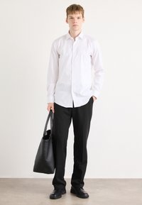 White button-up shirt, black trousers, and black leather tote bag. Smooth fabric with a classic fit. Minimalist design with no patterns.