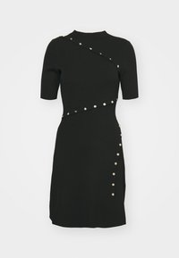 Robe noire ajustée à manches courtes avec un col montant, détails de boutons argentés en diagonale sur la poitrine et le long d’un côté jusqu’à mi-cuisse.