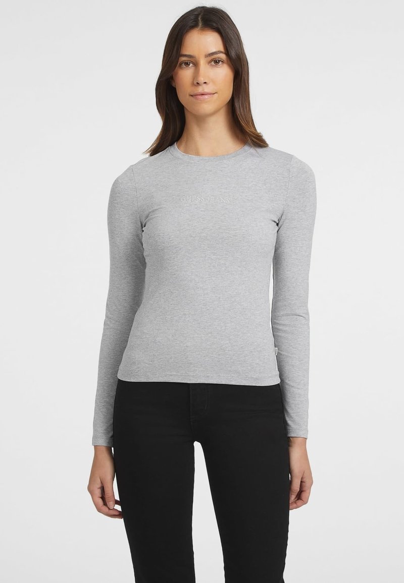 Pilkas ilgomis rankovėmis marškinėliai, pagaminti iš medvilnės mišinio, su prigludusia išvaizda. Priekinėje pusėje yra spausdintas "GUESS JEANS" logotipas, apvalaus iškirpimo.