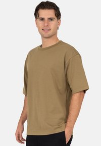 Oversized T-shirt in olijfgroen, gemaakt van zacht katoen, met een ronde hals en korte mouwen, een eenvoudig ontwerp en een ontspannen pasvorm.