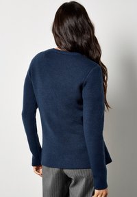 Marineblauer gestrickter Pullover mit rundem Ausschnitt und langen Ärmeln, der einen leicht ausgestellten Saum und eine angenehme Textur aufweist.