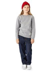 Grå sweatshirts med långa ärmar, blå denimjeans och vita sneakers; kombinerat med en röd stickad mössa med ett mönster av texturer.