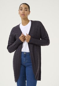 Cardigan lavorato a maglia grigio scuro con maniche lunghe, apertura frontale, motivo testurizzato e polsini a costine, abbinato a una camicia bianca e jeans blu.