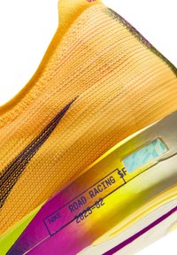 Zapatilla de running de competición de carretera Nike amarilla con logo negro y "2025-02" estampado en la entresuela amarilla y morada.