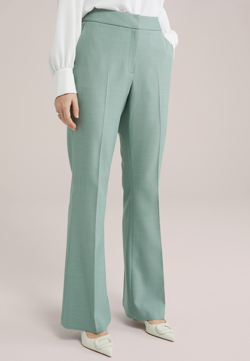 Pantalones de corte entallado verde claro con una textura suave y una forma acampanada. Cuenta con una cintura alta y dos bolsillos laterales.