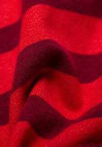 Rote gestreifte Stoff zeigt abwechselnd breite Streifen in leuchtendem Rot und dunklem Rot mit einem weichen, strukturierten Strickmuster.