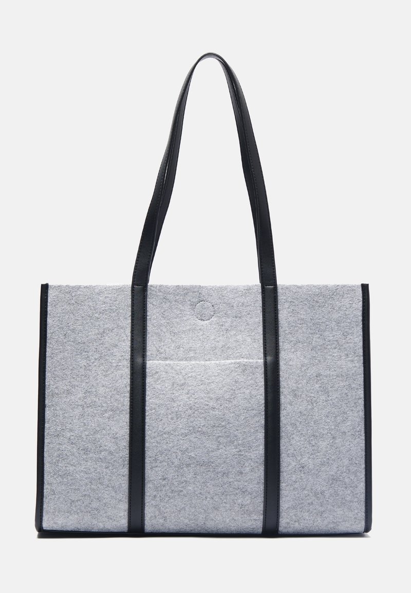 Grå tygväska med svarta läderhandtag, rektangulär form och en framsida med ficka, med en rund tryckknappslås upptill.