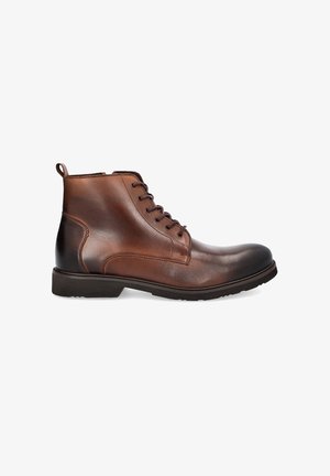 Brązowe skórzane botki za kostkę o gładkim wykończeniu, okrągłym nosku, sznurowaniu z przodu oraz pętelce z tyłu. Trwała gumowa podeszwa.