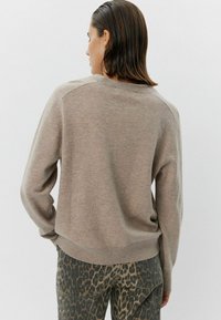 Pulover bej tricotat, cu guler rotund și mâneci raglan. Textură moale, siluetă casual, asociat cu pantaloni cu model leopard.