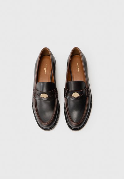 Mörkbruna läderloafers med rund tå, dekorativ rem och detaljer i guldton. Har en kontrasterande svart yttersula.