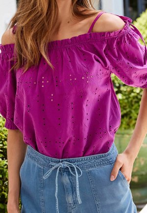 Blouse épaule dénudée fuchsia vif avec broderie à œillets, manches courtes bouffantes et liens d'épaule ajustables, associée à un short bleu clair avec cordon de serrage.