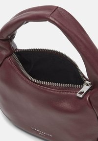 Bordowa skórzana torebka o zakrzywionym kształcie, z zamknięciem na zamek błyskawiczny, srebrnymi elementami zamka oraz miękką wyściółką wewnętrzną.