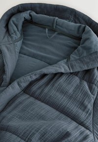 Dunkelblaue gesteppte Decke mit einer weichen Textur, die ein mehrlagiges Design und ein glattes Innenfutter aufweist, teilweise gefaltet dargestellt.