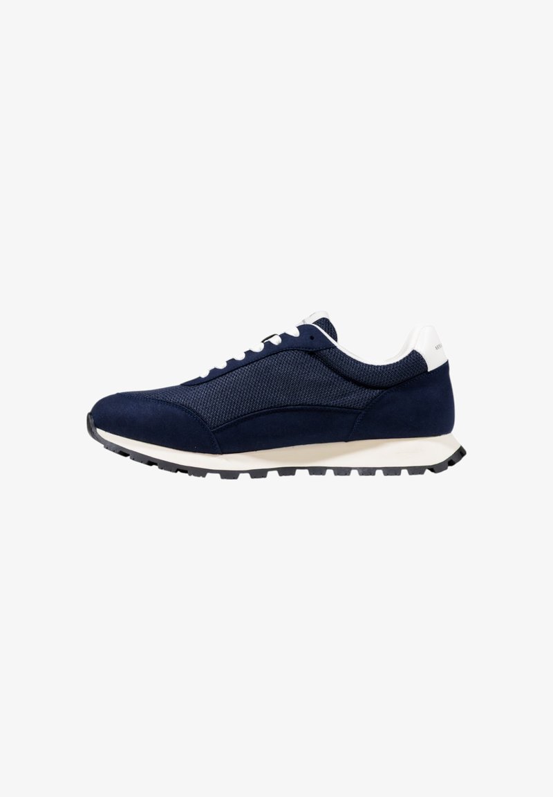 Zapatillas azul marino con parte superior de malla, acentos de ante, cordones blancos, suela de color claro y una suela exterior de goma negra texturizada.