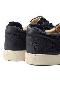 Navy leather sneakers with a textured finish, suede accents, cream rubber sole, and minimalist design, featuring rounded heels and low tops.