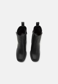Stivaletti neri in pelle con una texture liscia, design a punta quadrata e chiusura con zip laterale. Presentano una linguetta per facilitarne l'indossamento.