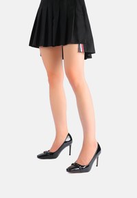 Décolleté in vernice nera con punta affusolata e dettaglio a fiocco, caratterizzate da un design elegante e un tacco a stiletto alto per un aspetto raffinato.