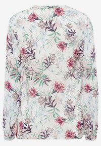 Blouse à manches longues avec une base blanche présentant un motif floral aux tons rouges, violets, verts et beiges.