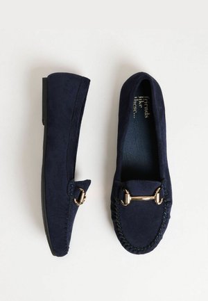 Tumši zili zamšādi loaferi ar zelta toņu aparatūru, stitched detaļām un plakanu zoli. Apaļa pirksta forma ar gludu virsmu.