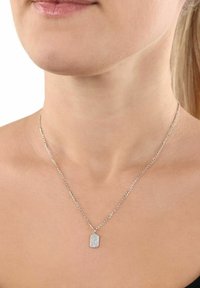 Silverhalsband med en strukturerad rektangulär berlock, hängande från en delikat kedja, uppvisad mot en neutral bakgrund.