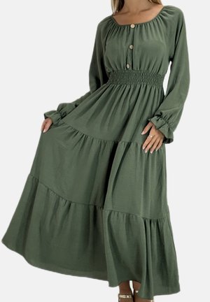 Abito lungo a balze di colore verde oliva con scollo quadrato, chiusura con bottoni e vita arricciata. Presenta maniche lunghe e una gonna fluente.