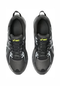 Black athletic shoes with mesh upper, rubber sole, and white accents. Rounded toe and laces; prominent logo in bright yellow on tongue.