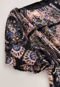 Zwarte stof met een kleurrijke paisley- en bloemenprint. Heeft opgeblazen mouwen, een geplooide taille en een gestructureerde, licht doorschijnende uitstraling.