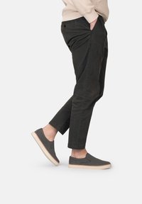 Donkergrijze instapschoenen met een stoffen bovenwerk en een beige rubberen zool. Gekocht bij een paar smalle zwarte broeken met de voet iets omhoog.