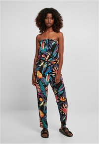 Mono negro sin tirantes con patrones florales y abstractos coloridos, cintura elástica, corte suelto y combinado con sandalias negras.