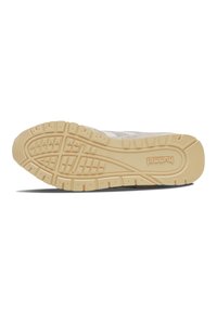 Białe sneakersy z teksturowaną cholewką, z gumową podeszwą w odcieniu beżowym. Wzór bieżnika zawiera rowki i wypukłe sekcje dla lepszej przyczepności.