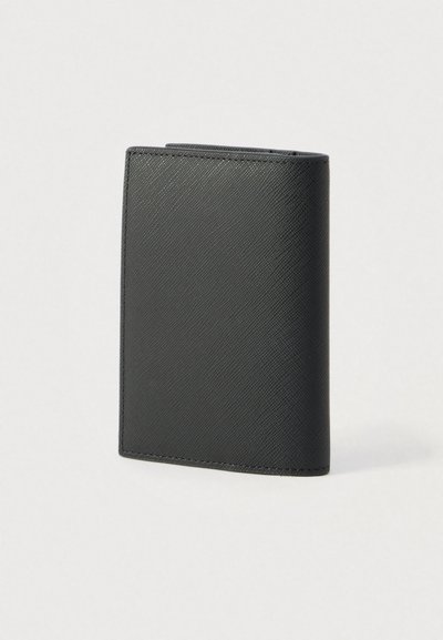 Fekete texturált bőr pénztárca, amely egy sima világos felületen áll függőlegesen, él menti varrással látható.