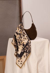 Braune Wildlederhandtasche mit geschwungener Silhouette, kombiniert mit einem cremefarbenen Schal mit Leopardenmuster und schwarzem Rand.