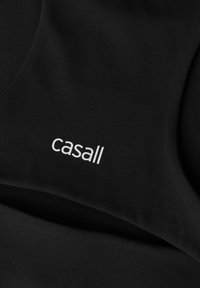 Czarna tkanina sportowa o gładkiej fakturze z wyraźnie widocznym białym logo "casall". Prosty, nowoczesny design, bezszwowe krawędzie.