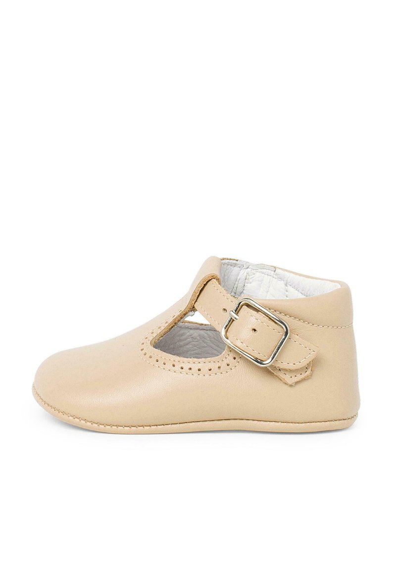 Scarpa in pelle beige con cinturino a T e fibbia, dotata di lati intagliati e dettagli perforati lungo il bordo superiore, texture liscia.