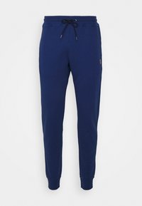 Navy blue sweatpants with a drawstring waistband, ribbed cuffs, and a small logo accent on the left side. Made from soft, textured fabric.