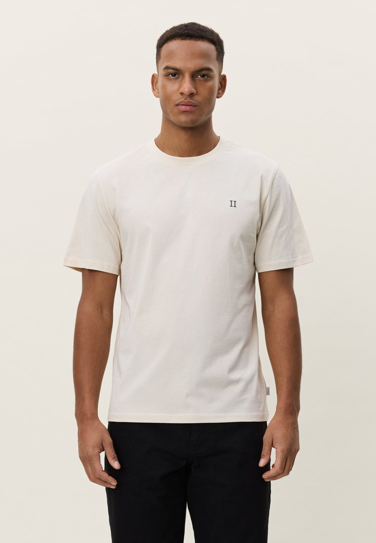 T-shirt beige clair en coton, avec un col rond et des manches courtes. Petit chiffre "II" foncé imprimé sur la poitrine.