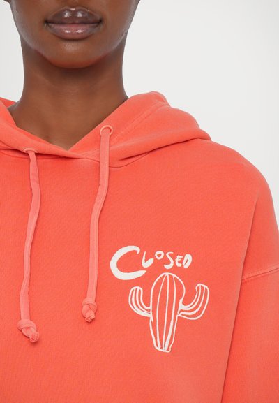 Korallefarbener Hoodie mit einem weißen Kaktus-Design und dem Text "Closed". Er hat eine Kapuze mit Kordelzug und einen weichen Stoffcharakter.