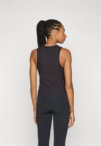 Top cropped preto com texturização em ribas. Sem mangas e com um acabamento texturizado, combinado com leggings pretas justas.