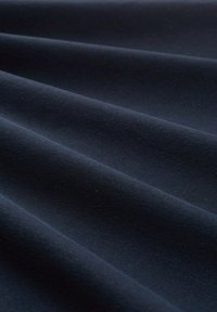 Niebieska bawełniana tkanina o gładkiej fakturze, z miękkimi fałdami tworzącymi delikatne fale na powierzchni.