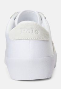 Vit sneaker med vit sula, suéde hälflik prydd med "Polo"-logotyp, sedd bakifrån mot en enkel bakgrund.