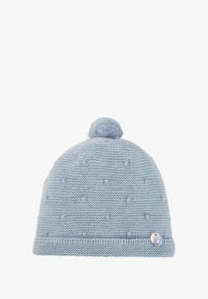 Bonnet en tricot bleu avec un pompon sur le dessus, présentant un motif texturé et une petite étiquette métallique sur le côté.