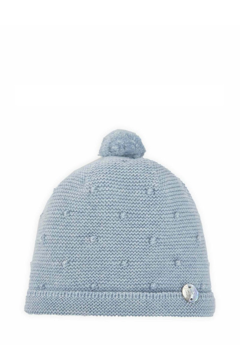 Bonnet en tricot bleu avec un pompon sur le dessus, présentant un motif texturé et une petite étiquette métallique sur le côté.
